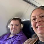 Marcus and Mardra "selfie" on airplane. Smiling and Marcus wearing headphones